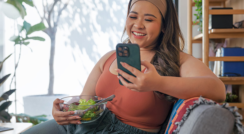 women eating salad while on phone