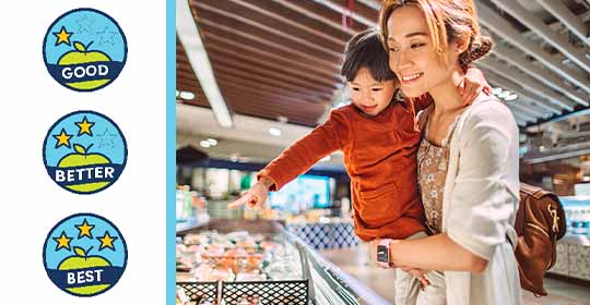 Woman holding her child in the grocery store with the guiding stars logos on the left