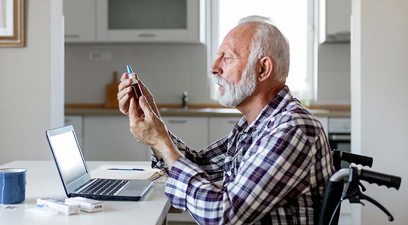 person sitting in front of laptop looking at medication