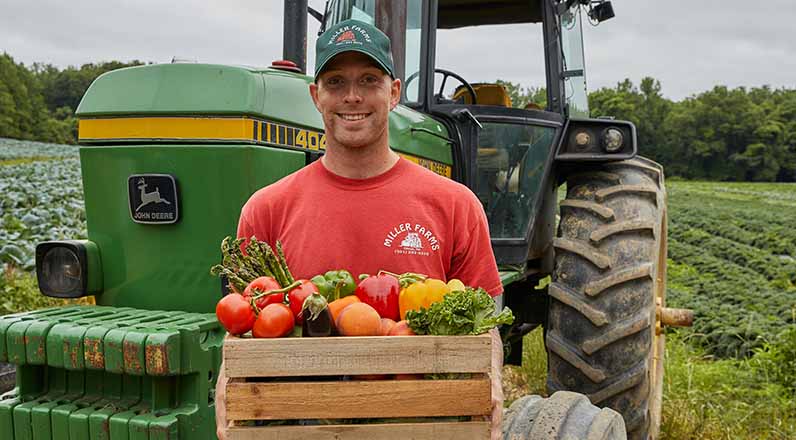 A farmer holding a crate of fresh produce