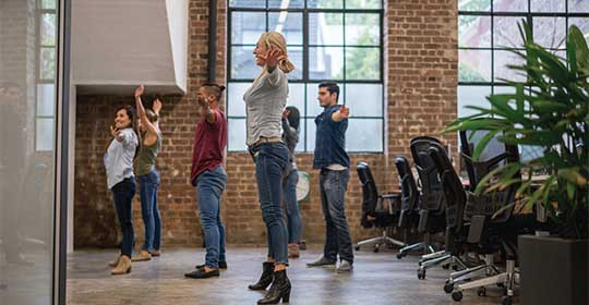 Coworkers doing some yoga in their shared office space